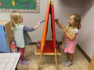 Two children drawing on an easel