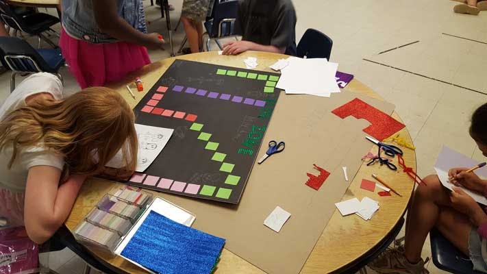 Children working on a board game project at a round table