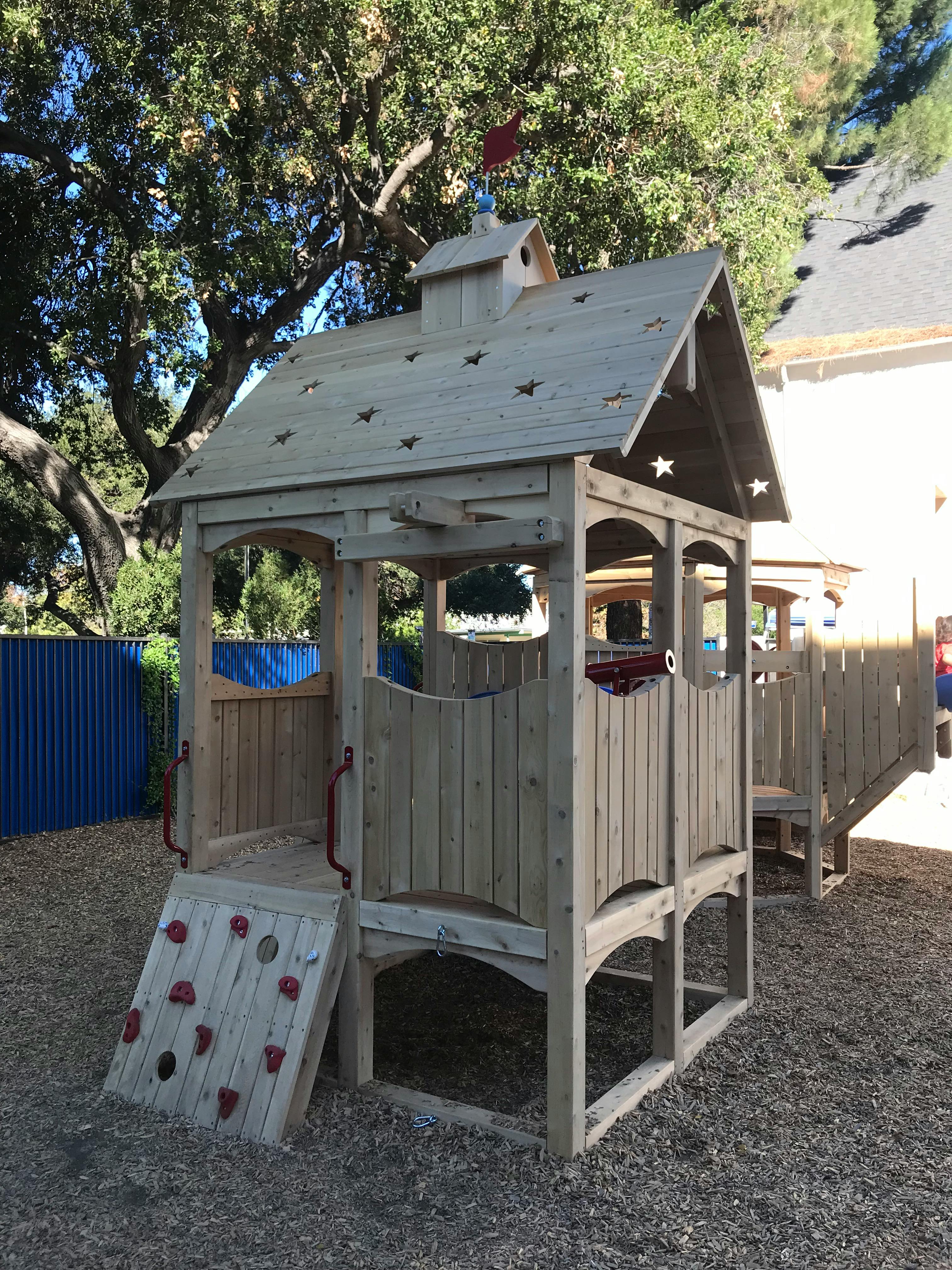 Wooden play structure with climbing wall in a playground