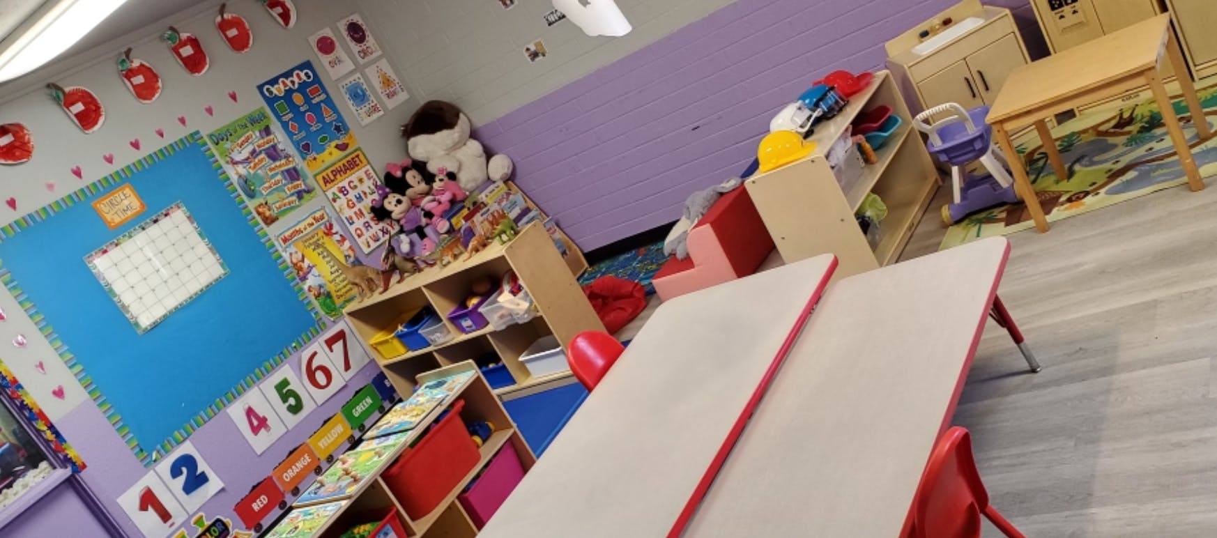 Classroom with tables, shelves, and educational posters on the wall
