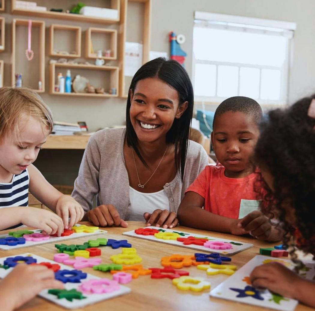 Adult and children playing with colorful shape puzzles at a table