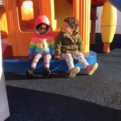 Two children sitting on a playground structure