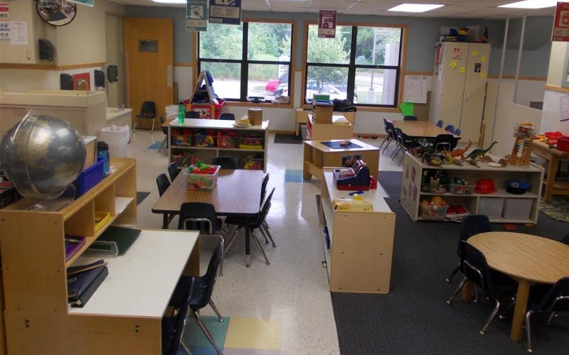Classroom with child-sized tables and chairs, shelves with toys, and large windows