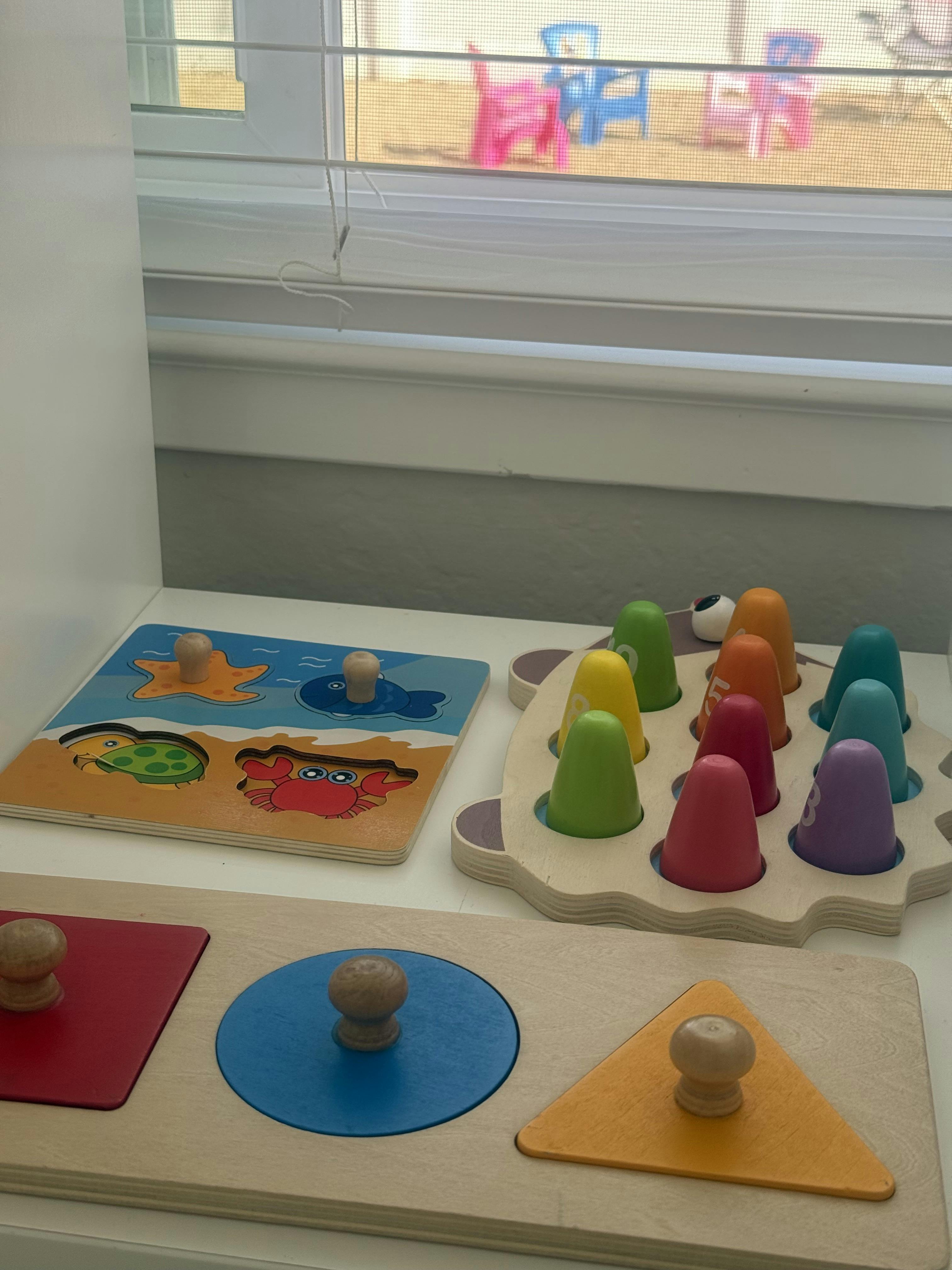 Wooden peg puzzles and a number sorting toy on a white surface