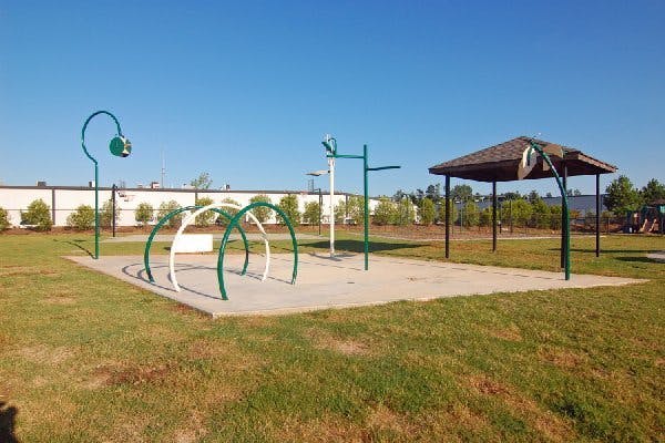 Outdoor splash pad with green and white arches and a nearby gazebo