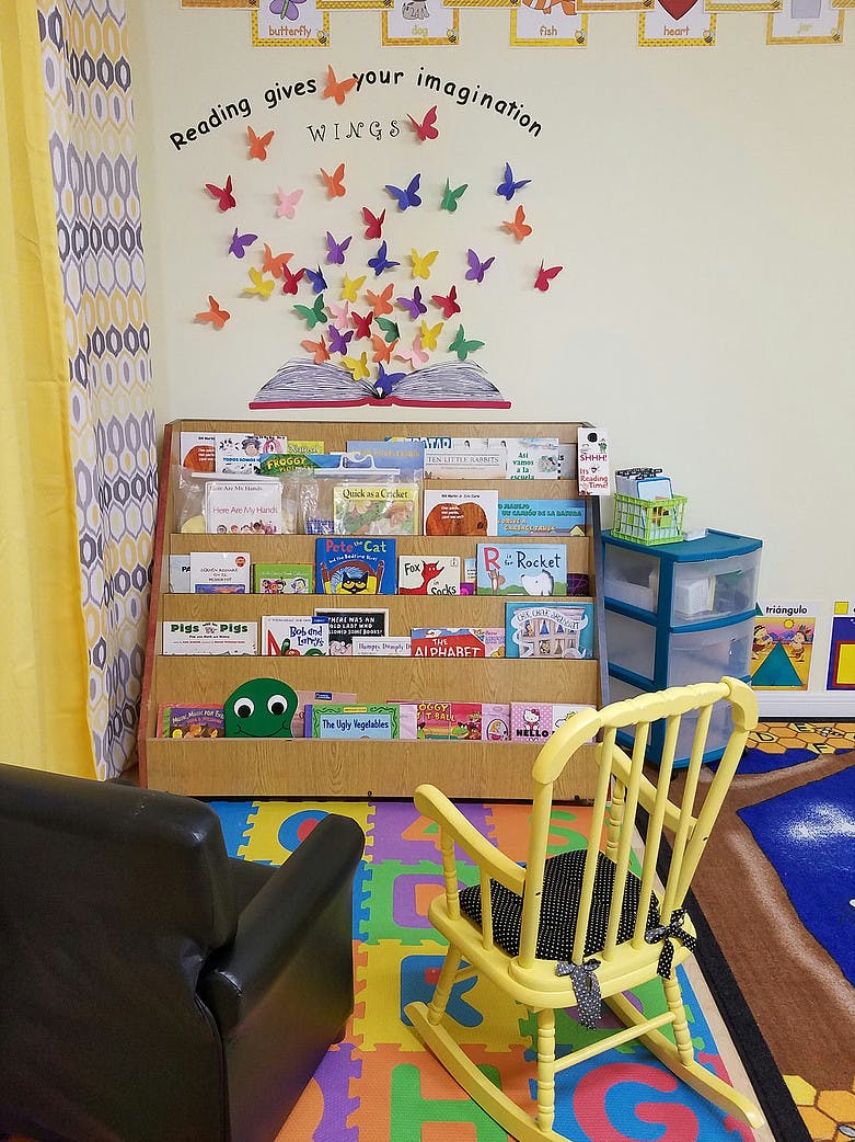 Children's reading corner with a bookshelf, chairs, and wall decor