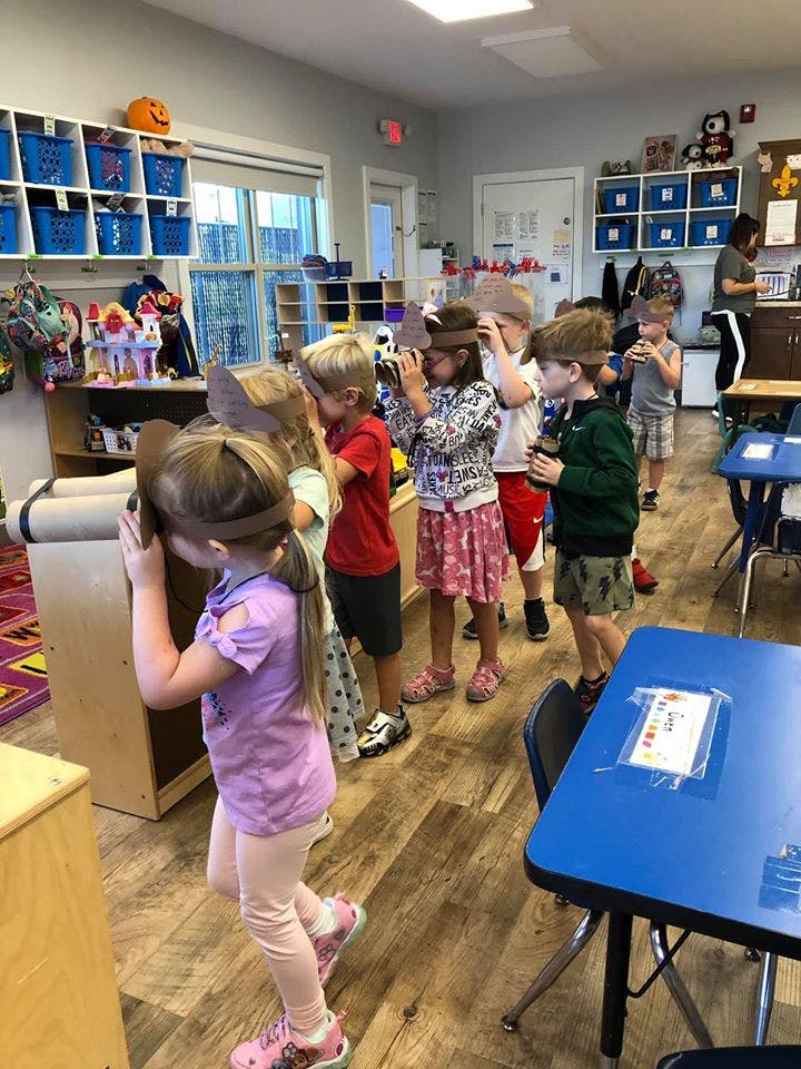 Children in a classroom looking through cardboard binoculars