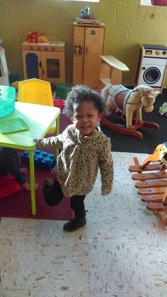 Child standing on one leg in a classroom