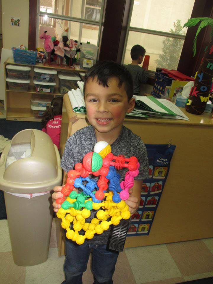 Child holding a colorful toy made of interconnected plastic pieces