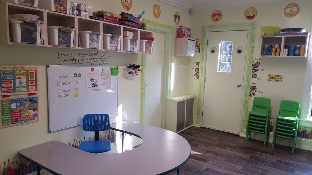 Classroom with a whiteboard, a blue chair at a table, and stacked green chairs