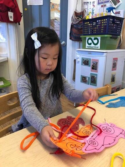 Child lacing felt shapes at a table