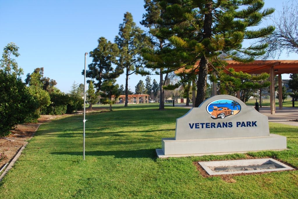 Veterans Park sign on a grassy lawn with trees in the background