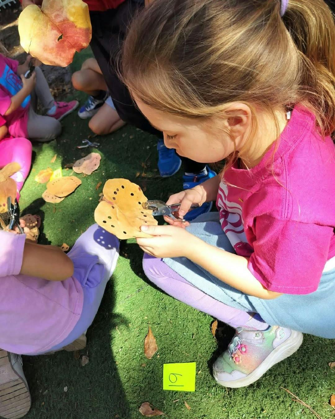 Child using a tool to work on a craft project outdoors