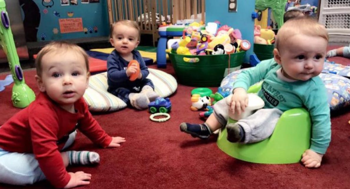Three children on a red carpet, one in a green seat