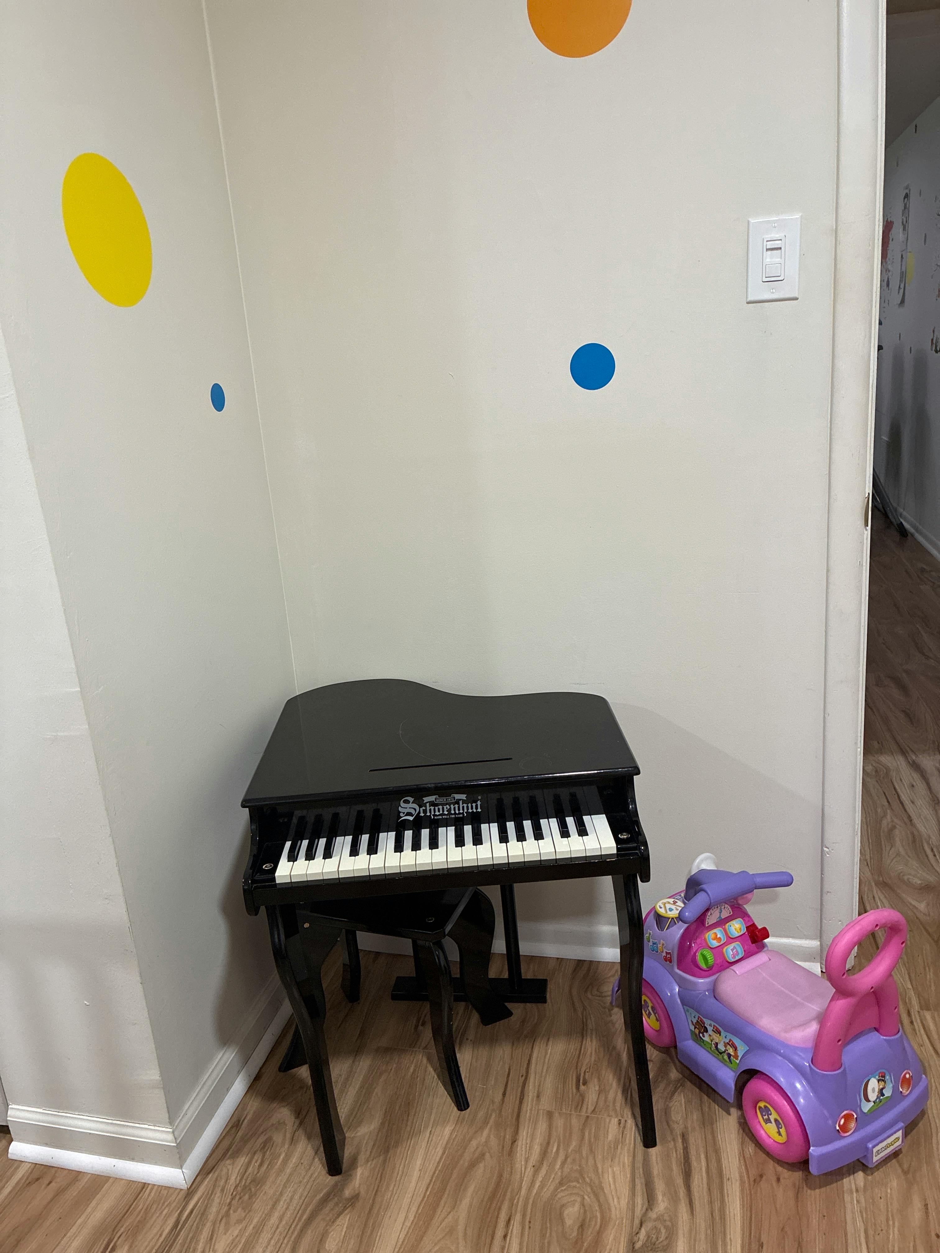 A black toy grand piano next to a purple and pink ride-on toy