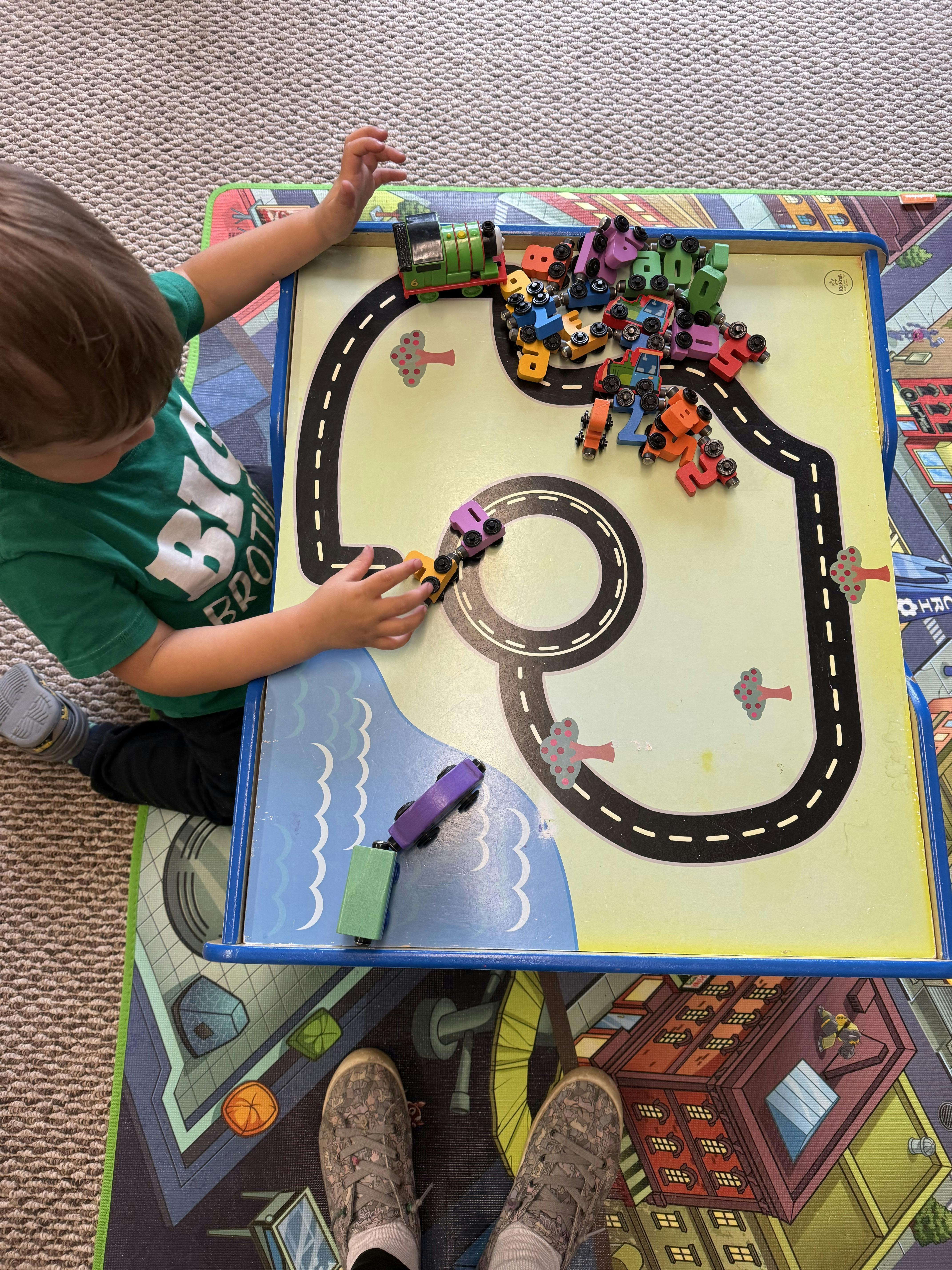 Child playing with toy cars on a playmat with roads