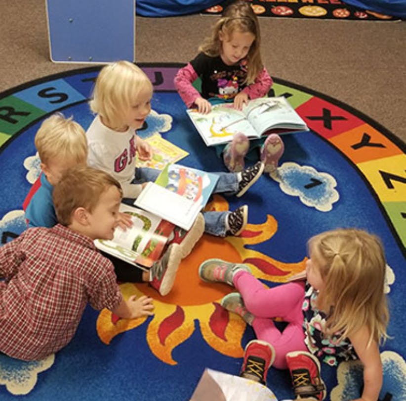 Children sitting on a rug reading books