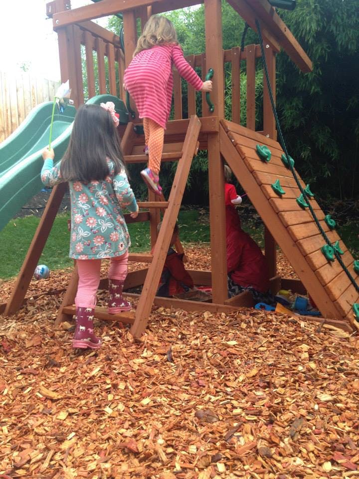 Two children climbing on a wooden playset