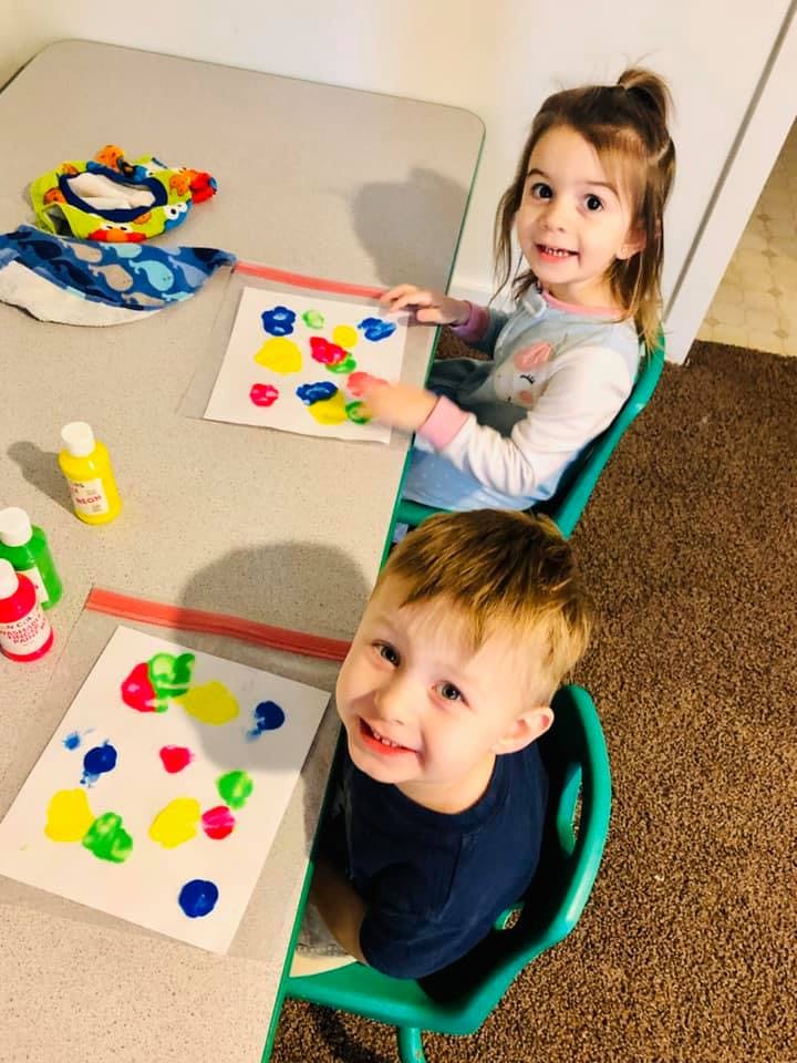 Two children finger painting at a table