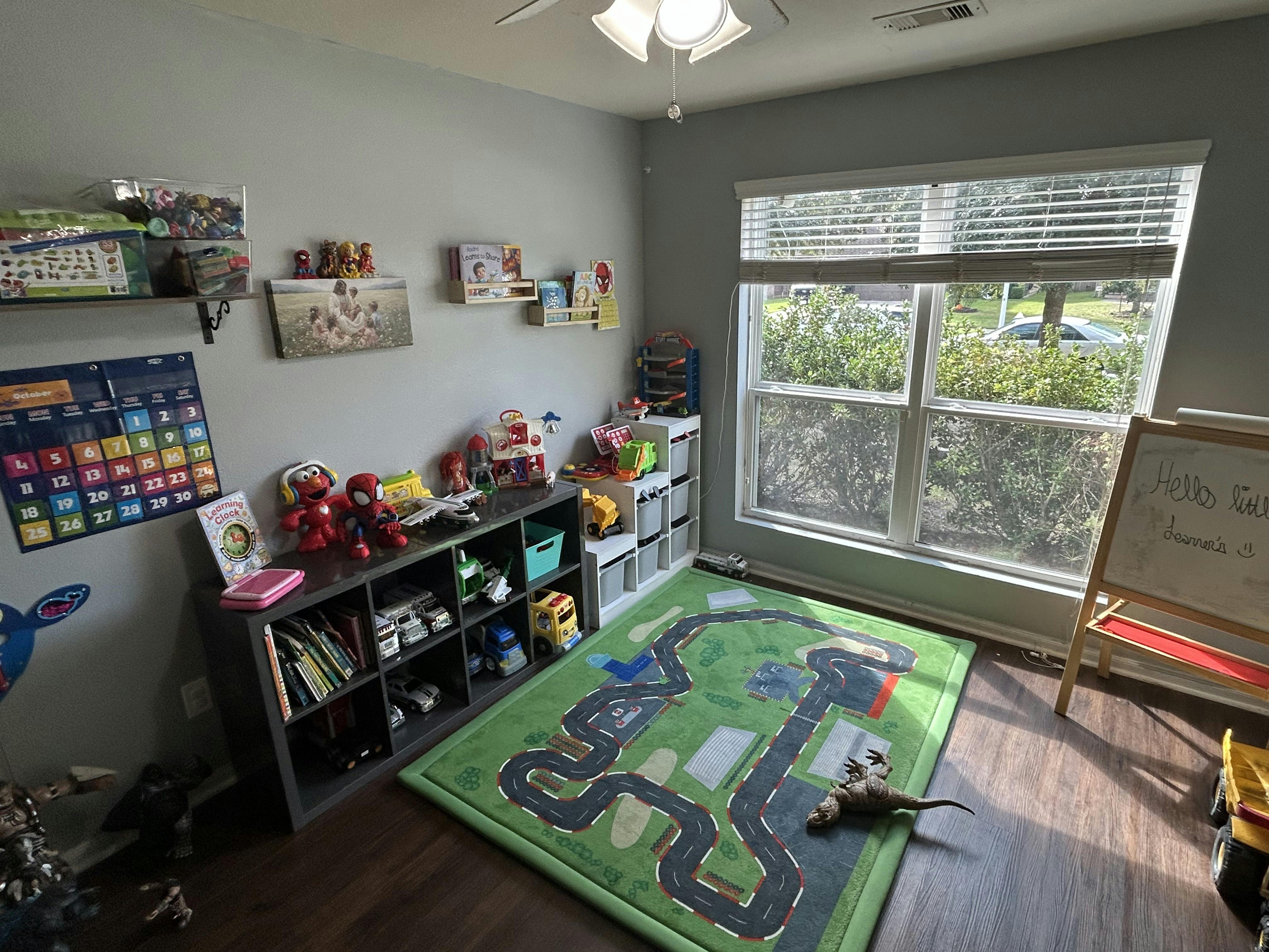 A child's playroom with toys, a shelf, and a road-themed rug