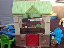 Child's playhouse with green roof and red door