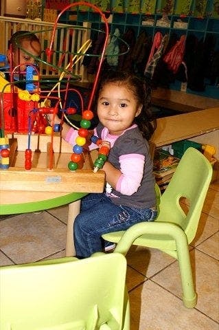 Child playing with a bead maze toy at a table