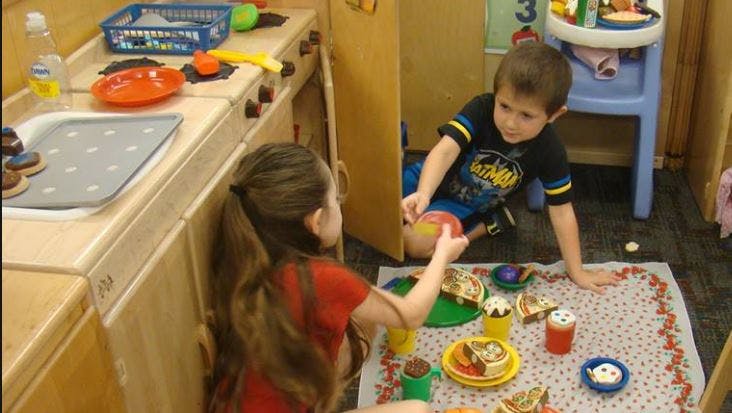 Two children playing with toy food on a mat