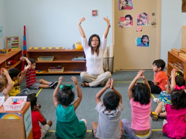 Person leading children in an activity in a classroom