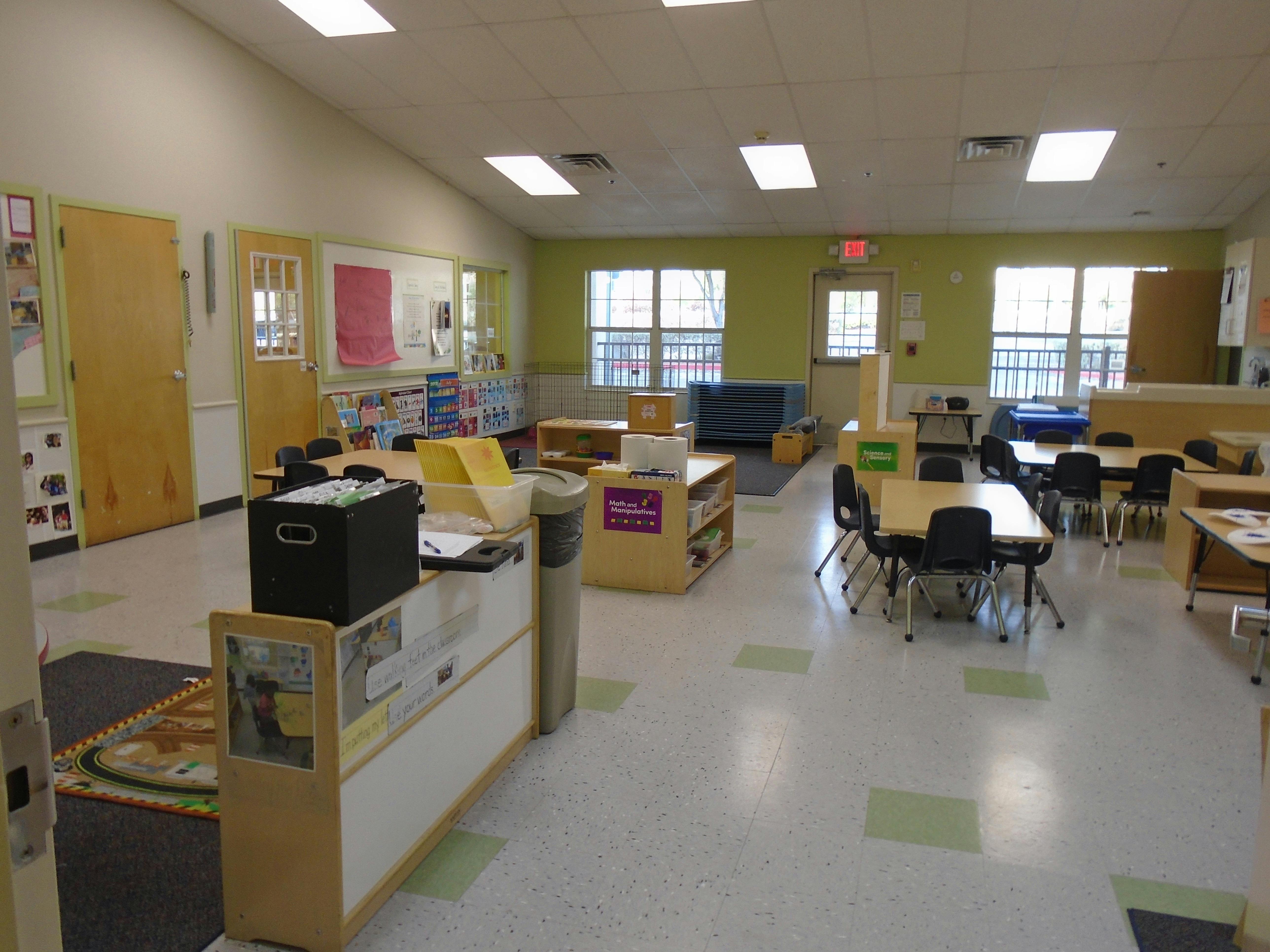 An empty classroom with tables and chairs, and various learning stations