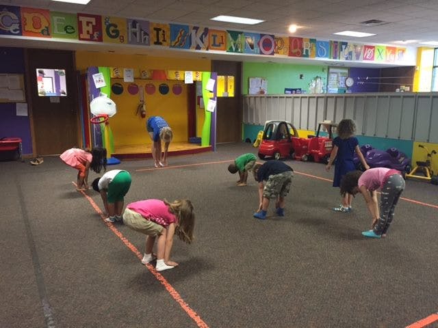 Children bending over in a classroom