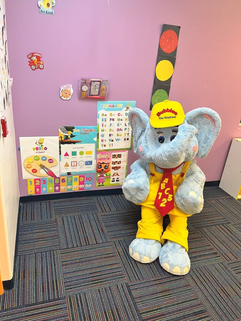 Elephant mascot wearing a yellow hat and overalls with a red tie