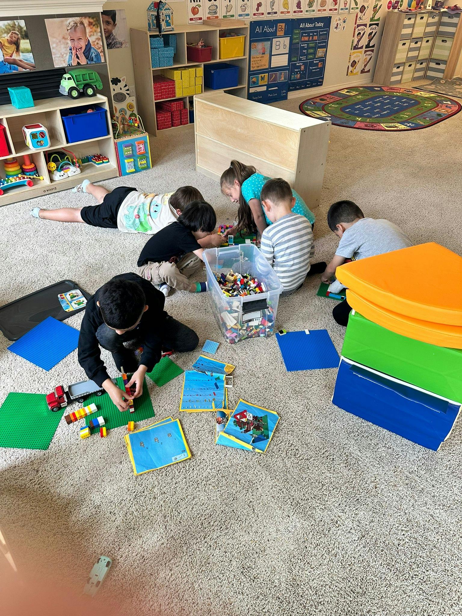 Children playing with building blocks on a carpeted floor in a classroom
