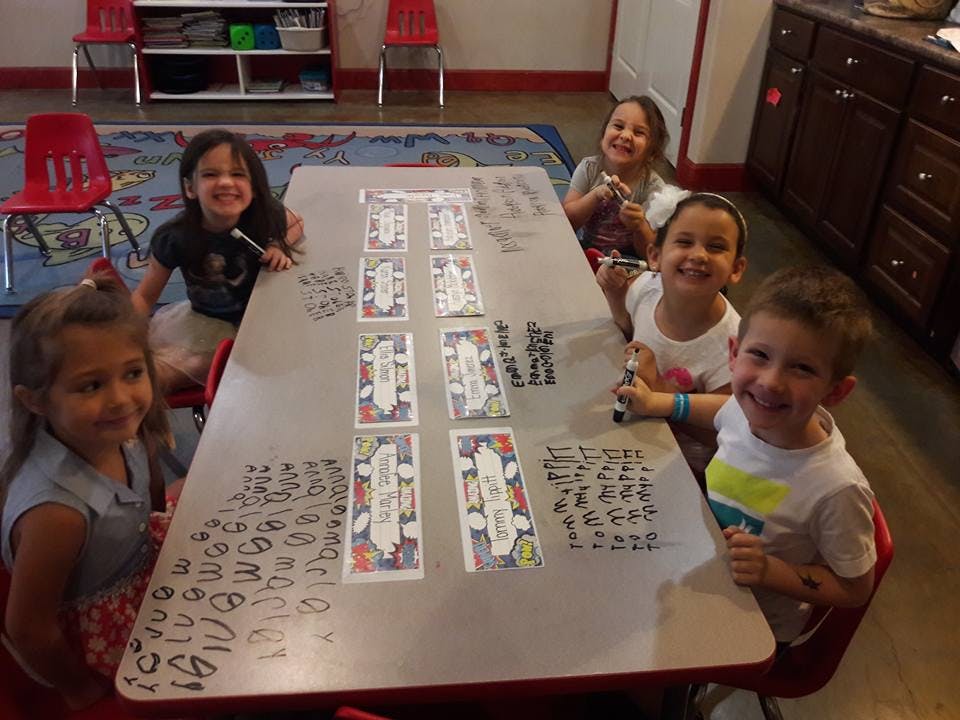 Children sitting at a table with cards and writing