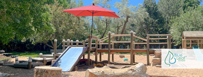 Playground with a slide, wooden structures, and a red umbrella