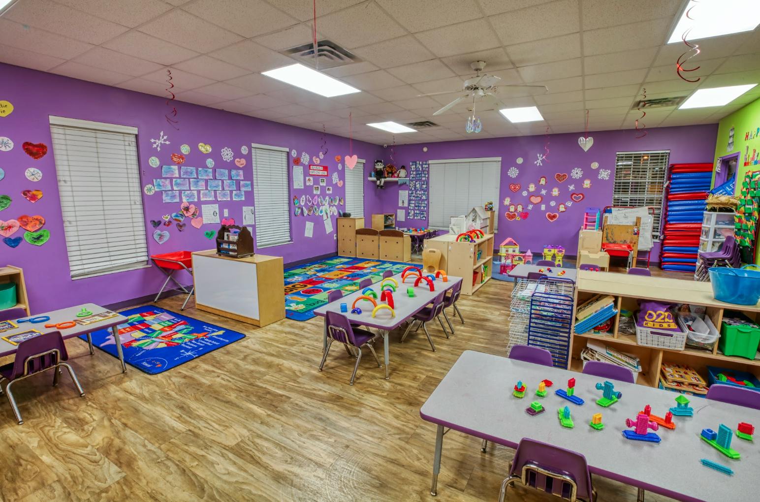 Colorful classroom with child-sized tables and chairs and activity rugs