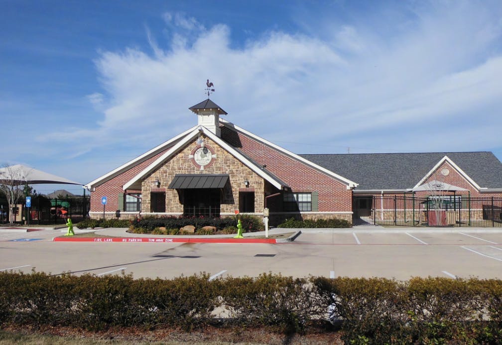 Building with brick and stone facade, cupola, and parking lot