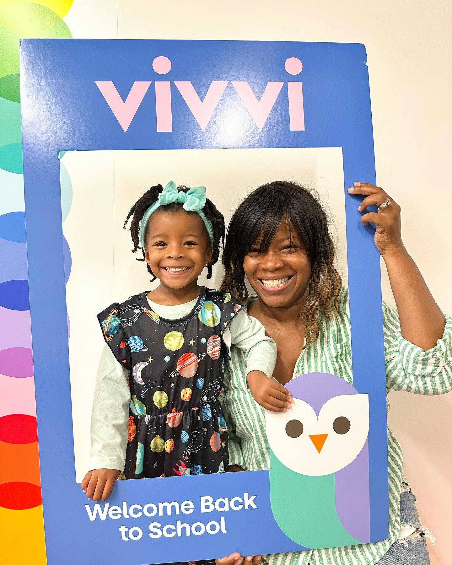 Person and child posing in a photo frame with "Vivvi" and "Welcome Back to School"