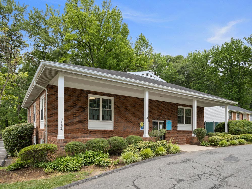 Brick building with white pillars and landscaping, street number 7136