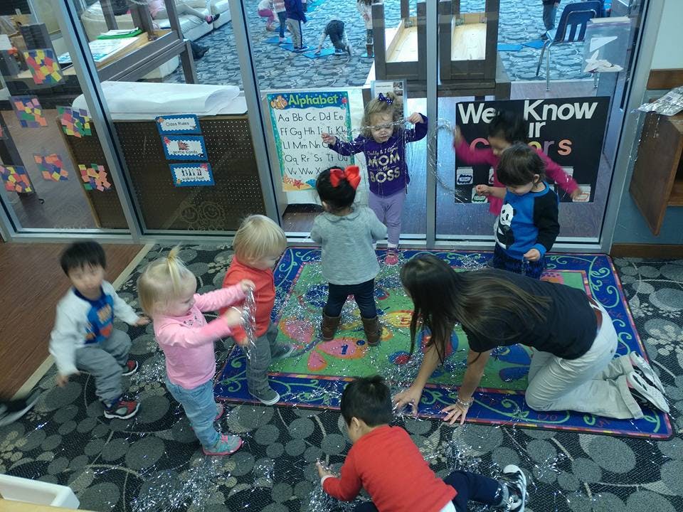 Adult and children playing on a rug in a classroom