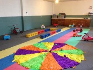 Playroom with colorful mat, toys, and a parachute