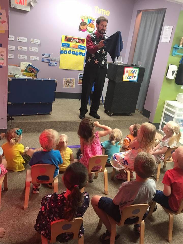 Person performing magic for a group of children in a classroom