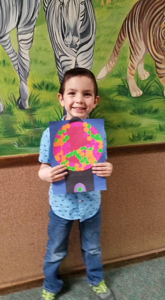 Child holding up a paper craft of a gumball machine