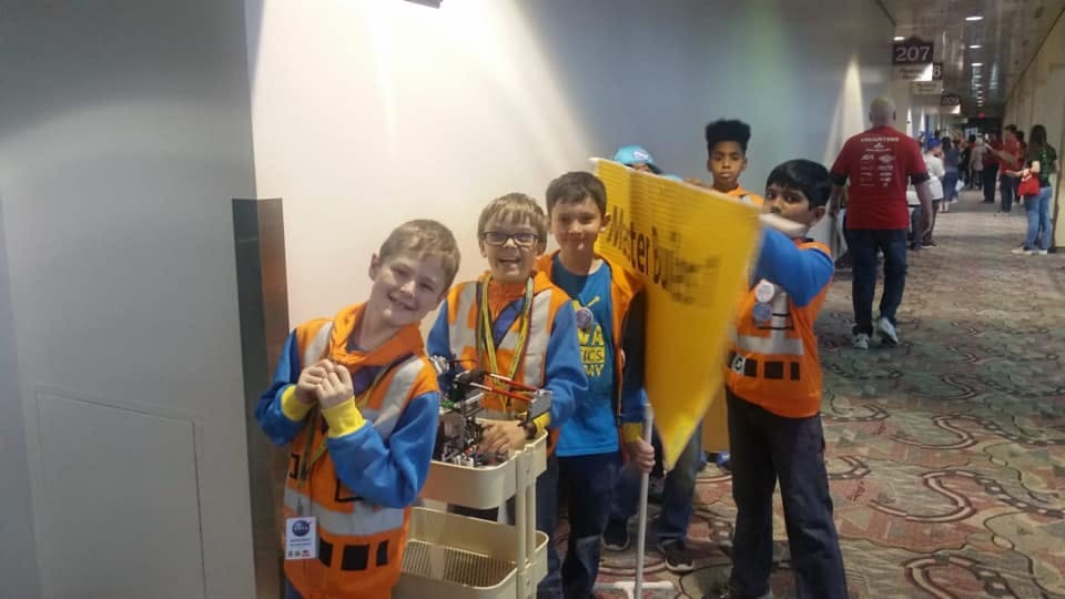 Children in costumes holding a yellow flag in a hallway