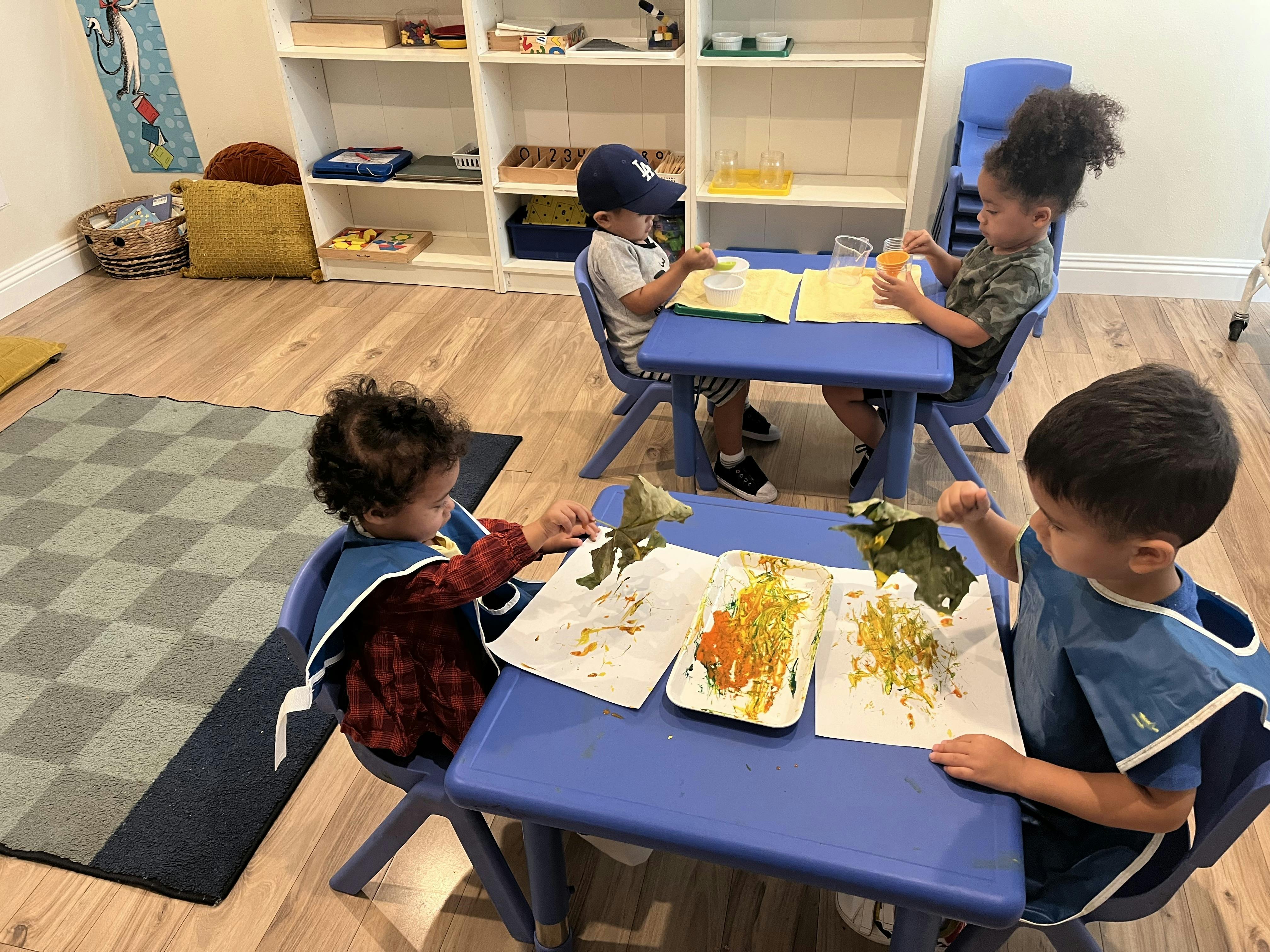 Children at blue tables doing art projects in a classroom