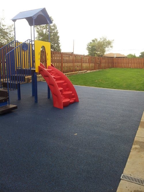 Playground with blue and yellow structure, red slide, and dark blue ground