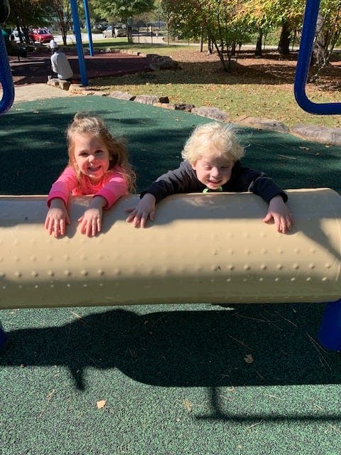 Two children looking over a playground barrier