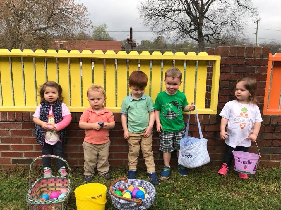Five children standing with baskets and buckets of colorful eggs