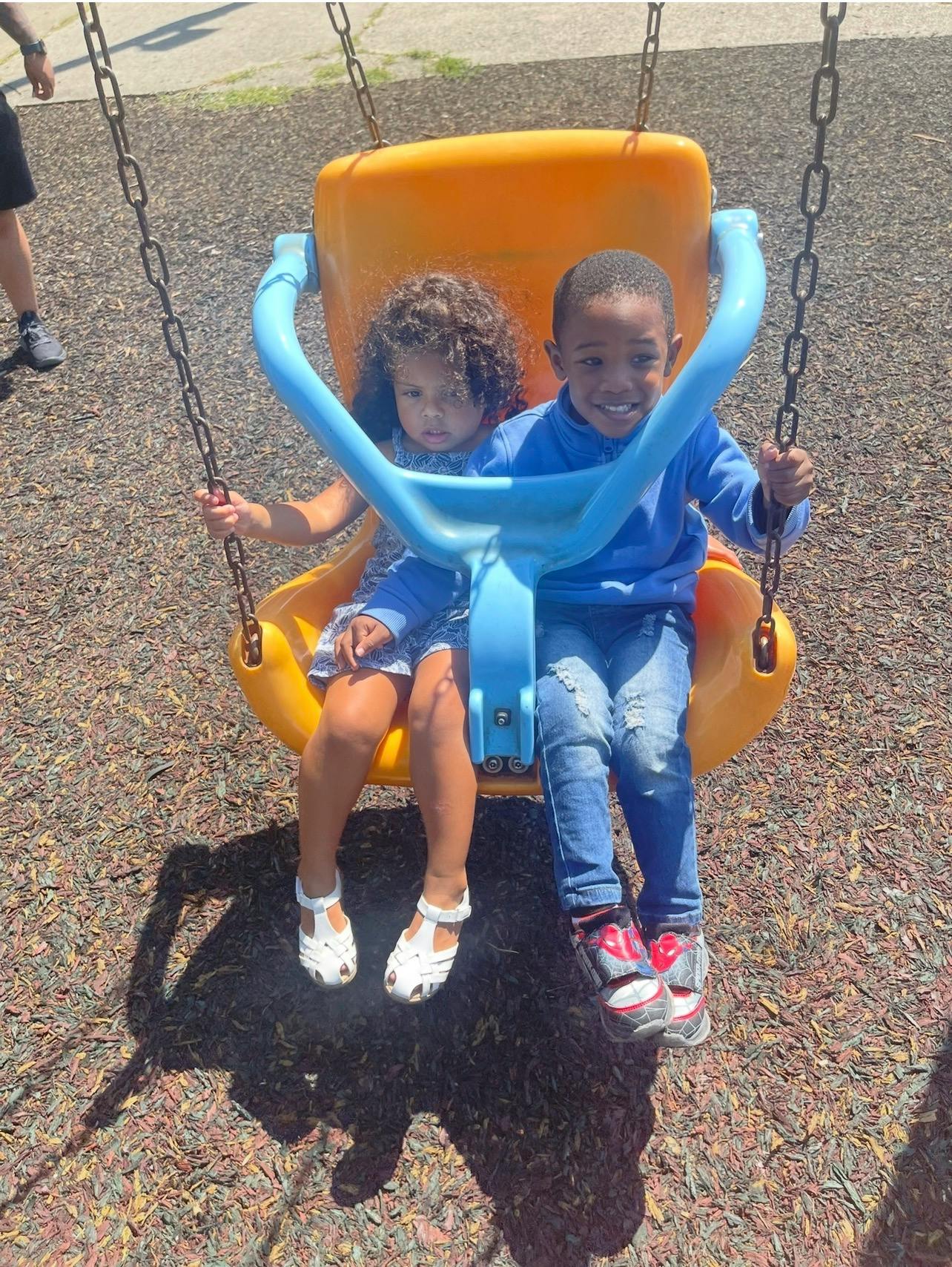 Two children sitting together on a playground swing