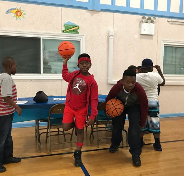Children playing with basketballs in a gym