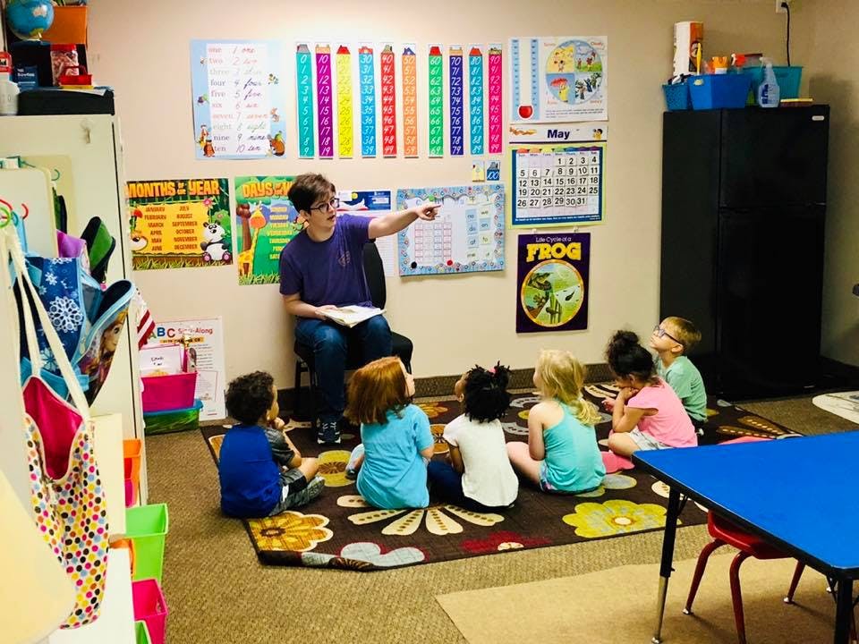 Adult reading to children sitting on a rug in a classroom